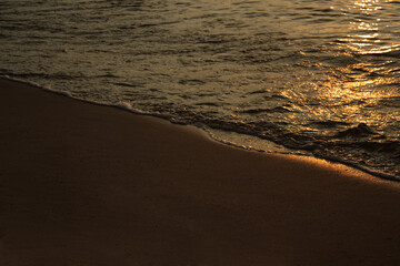 Sandy beach against the backdrop of sea waves at sunset