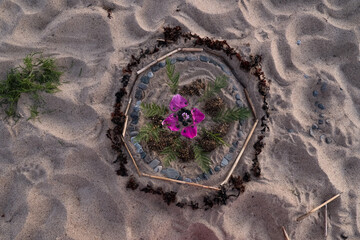 Mandala on ground. Making a mandala of natural elements on a beach. Handmade nature art pattern.