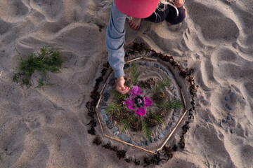Mandala on ground. Making a mandala of natural elements on a beach. Handmade nature art pattern.