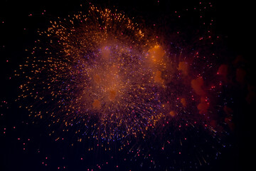 Bright orange and blue sparks of fireworks on the background of the night sky. High quality photo