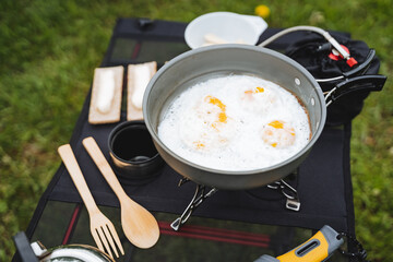 Delicious delicious scrambled eggs cooked in camping conditions on a tourist burner, hiking cuisine, breakfast in the mountains, cutlery, climber's equipment.