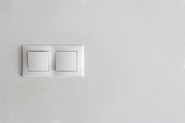 Light switch. White plastic mechanical switch installed on light gray wall. Turn on white light, turn lights on or off. Electric switch