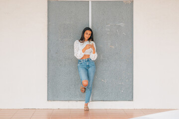 Fototapeta premium latin girl on the wall with mobile phone