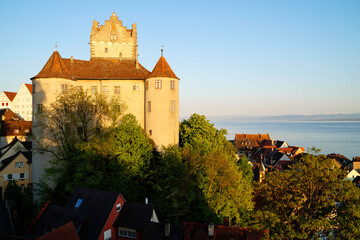 Northwest side of romantic medieval Meersburg castle or Burg Meersburg on Lake Constance (or Bodensee) and the Alps in the background on a sunny spring evening with clear blue sky (Meersburg, Germany)