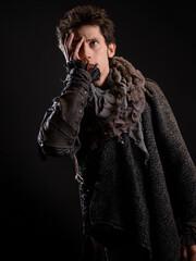 A guy in a steampunk or post-apocalyptic image, he covered his face with his hand. portrait on a black background