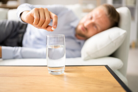 Man With Hangover Taking Medicine Pill