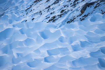 Snow texture. Wind sculpted patterns on snow surface. Wind in the tundra and in the mountains on the surface of the snow sculpts patterns and ridges (sastrugi). Arctic, Polar region. Winter background