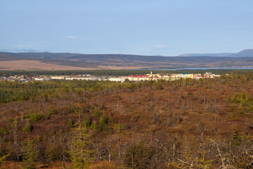 View of the northern town and forest-tundra. Colored buildings in the distance. Nature and settlements of Siberia. Surroundings of the urban-type settlement of Ola. Magadan region, Far East of Russia.