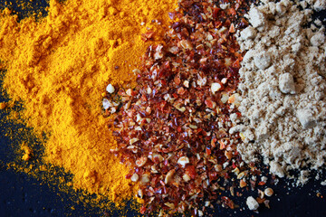 turmeric, chili and galgant powder on a table, different colorful spices on a table as backgroundpices