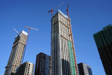 Fototapeta na wymiar High-rise buildings under construction against a clear blue sky. Housing construction.