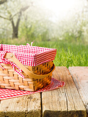 On a simple wooden table, a straw picnic basket against the backdrop of a bright summer nature....