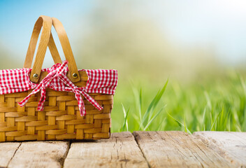 Against the background of green juicy grass, a beautifully decorated picnic basket on a wooden...