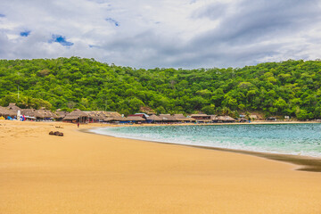 Huatulco bays - Maguey beach. Beautiful beach with pristine waters, with turtles and fishes. Mexican beach with wooden huts by the sea - obrazy, fototapety, plakaty