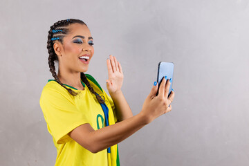 Brazilian fan woman cheering for brazil at world cup 2022 on video call talking to friends...
