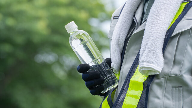 プラスチックボトルの水を持つ作業服の男性｜建設業の熱中症対策イメージ