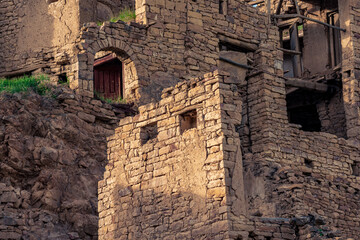 ruins of stone houses attached to the rock in the ghost village of Gamsutl in Dagestan