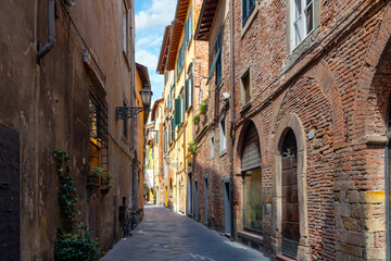 Fototapeta na wymiar A typical street of shops and cafes inside the walled medieval city of Lucca, Italy, in the Tuscany region.