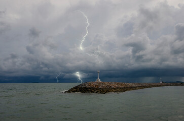 Seawall with small light houses in the sea with strong lightning far away