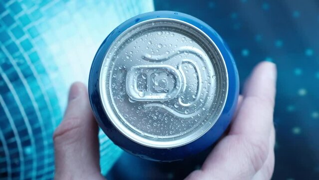 hand takes a metal can of a cool drink