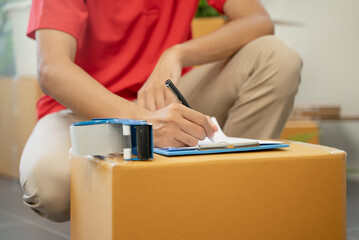 Asian moving service man checking the list of stuff before packing to cardboard for relocation move out of the apartment.