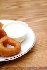 Fried onions served in small white plates in American restaurants.