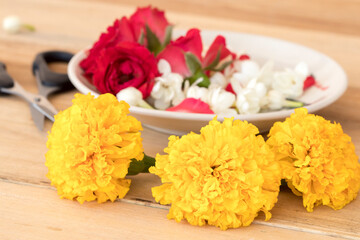 marigold, rose and jasmine on dish arrangement  flat lay postcard style on background wooden