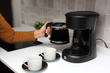 Woman's hands serve coffee prepared in a coffee maker to start the day with the benefits of antioxidants, protects against cancer, fights Alzheimer's and Parkinson's
