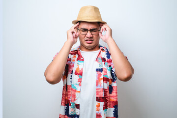Obraz na płótnie Canvas Young handsome asian man wearing casual beach shirt and bucket hat with hand on head for pain in head because stress.