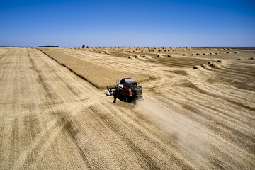 a combine harvester harvesting a field of wheat against a blue sky rural landscape