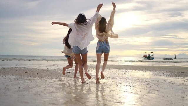 4K Group of Young Asian woman in walking and playing together on tropical beach at summer sunset. Happy female friends enjoy and fun outdoor activity lifestyle on holiday travel vacation at the sea