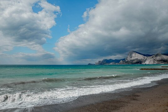 emerald sea against the background of mountains and sky with dark clouds