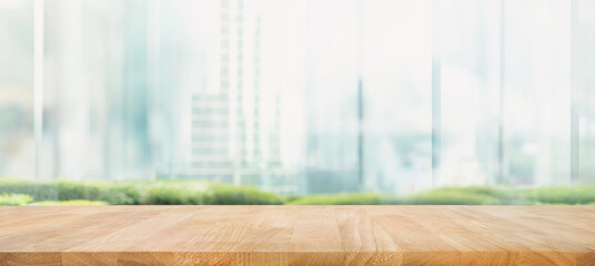 Selective focus.Top of wood  table with window glass and cityscape background.