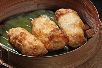 Crispy fried tofu skin dim sum with prawns and chicken served in a bamboo container, Traditional Chinese cuisine on blur background; dim sum