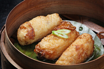Crispy fried tofu skin dim sum with prawns and chicken served in a bamboo container, Traditional Chinese cuisine on blur background; dim sum