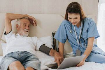 Asian nurse measuring blood pressure of elderly man at home. Young nurse helping senior man at home. Senior health care.