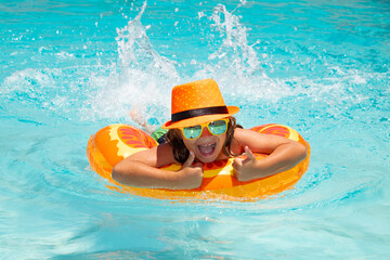 Kid splashing and swimming in pool. Swim water sport activity on summer vacation with child.
