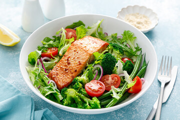 Grilled salmon fish fillet and fresh tomato vegetable salad with lettuce, arugula, broccoli and green beans. Healthy food, mediterranean diet