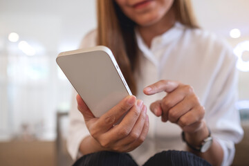 Closeup image of a young woman holding and using mobile phone