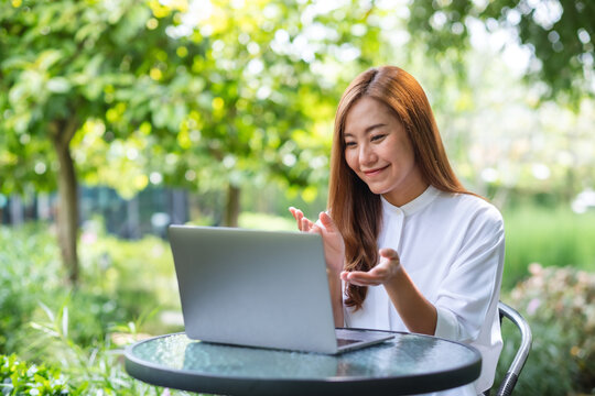 Portrait image of a young woman using laptop computer for video call and working online in the outdoors