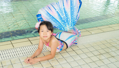 温水プールでマーメイドを練習している可愛い小学生の女の子の姿