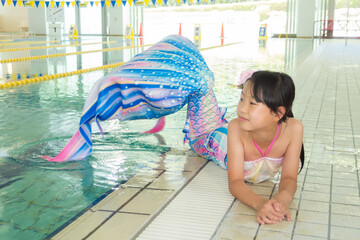 温水プールでマーメイドを練習している可愛い小学生の女の子の姿