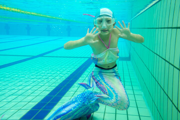 温水プールでマーメイドを練習している小学生の女の子の水中写真