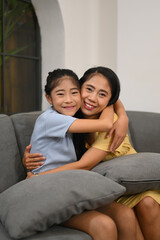 Obraz premium Adorable asian child cuddling mother and smiling at camera. Love and support in family relationships