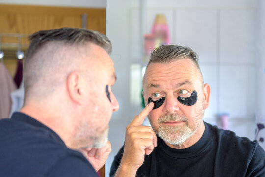 Middle-aged man applying gel hydration patches to eyes