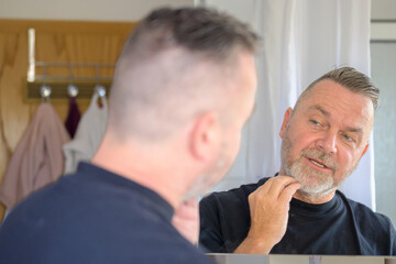 Man checking out his neatly trimmed beard in the mirror