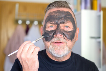 Man applying a face mask with a cosmetic brush