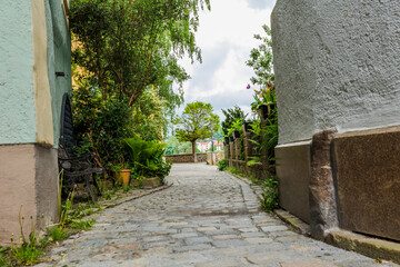 2022-05-13, GER, Bayern, Passau: Ein typischer Weg in der passauer Altstadt mit Kopfsteinpflaster fürht direkt auf einen Baum am Fluss Inn zu.