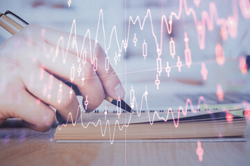 Double exposure of man doing notes of stock market with forex graph.