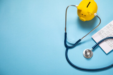 Piggy bank with stethoscope and calculator on the blue background.