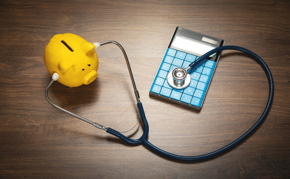 Piggy bank with stethoscope and calculator on the wooden background.